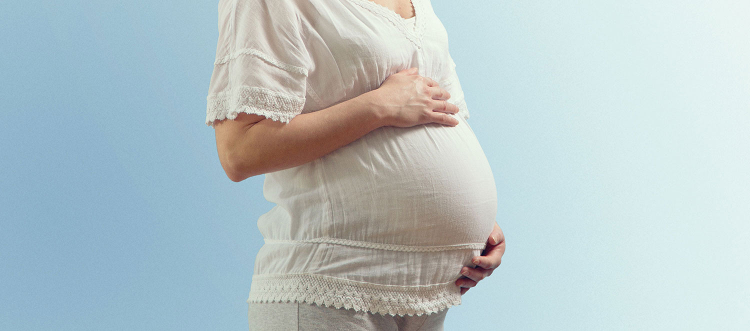 Bauch einer Schwangeren vor blauem Hintergrund