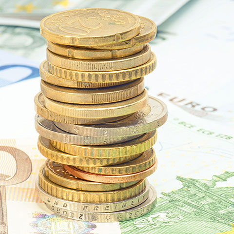 Ein Stapel Euro-Münzen und Geldscheine. 