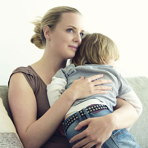 Auf dem Sofa: Frau hält Kind im Arm. 
